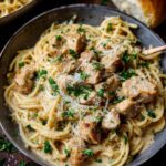 A close-up of a bowl of creamy garlic parmesan chicken pasta, topped with shredded cheese and parsley.