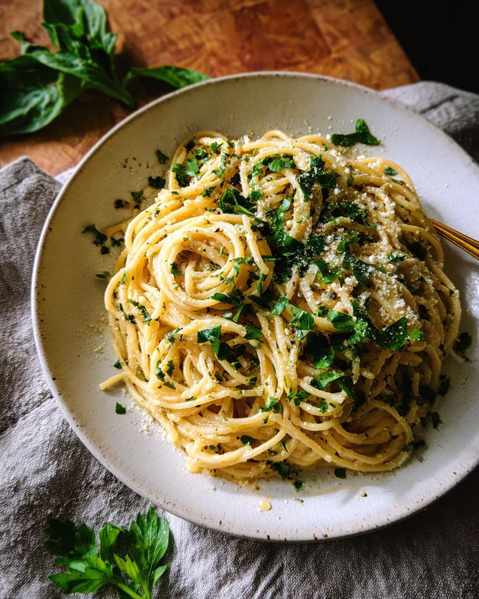 A close-up of a plate of spaghetti tossed with fresh herbs and Parmesan cheese, a perfect example of Pasta Recipes With Fresh Herbs.