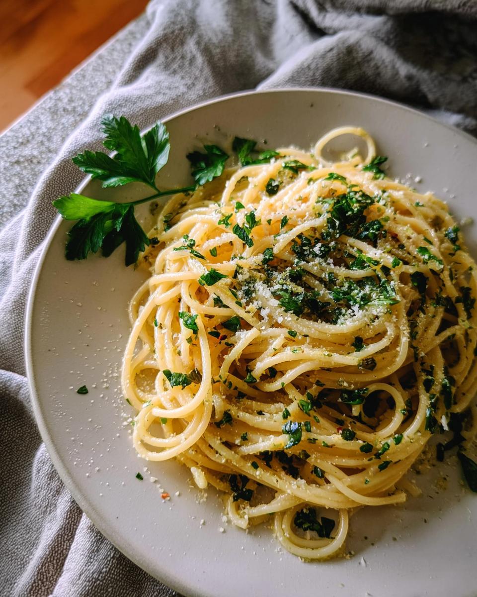 A close-up of spaghetti tossed with fresh herbs and grated cheese, showcasing one of the best pasta recipes with fresh herbs.