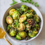 Close-up of a bowl of roasted Brussels sprouts, seasoned with Parmesan and herbs, a perfect Thanksgiving side dish.