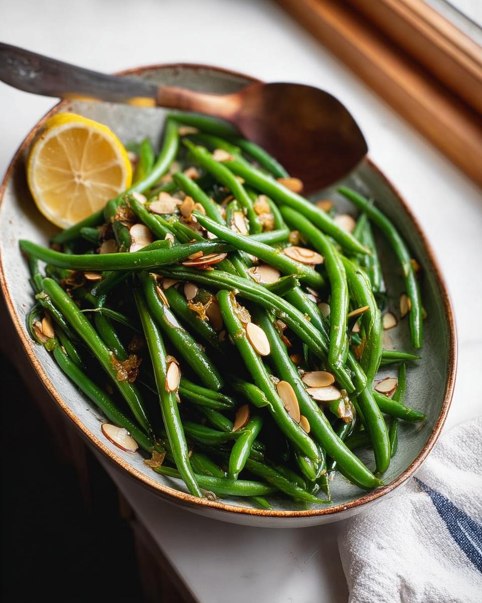 A cozy Thanksgiving side dish of fresh green beans tossed with toasted almonds and a lemon wedge.