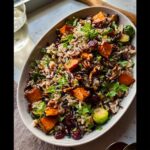 A festive Thanksgiving side dish of wild rice salad with roasted sweet potatoes, Brussels sprouts, pecans, and cranberries.