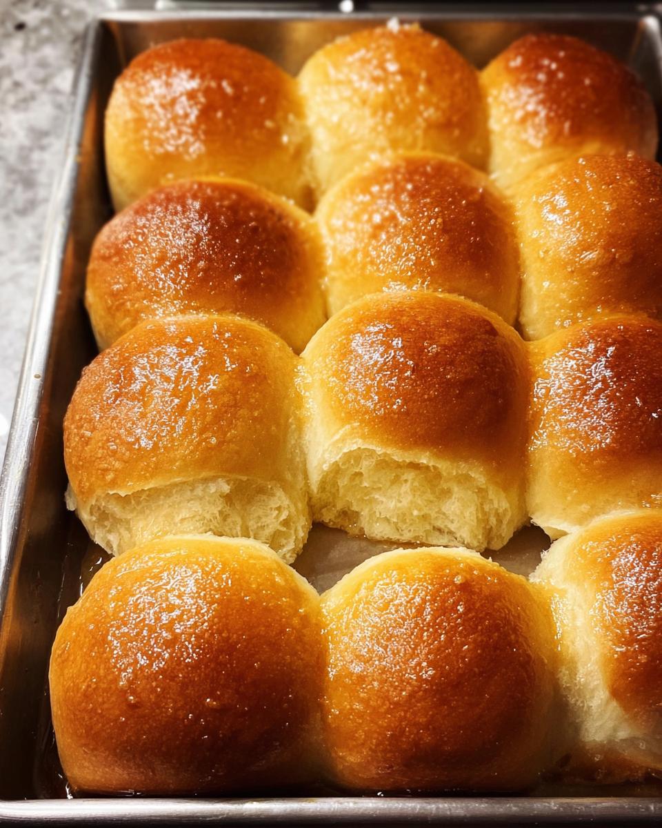 Close-up of golden brown, buttery dinner rolls arranged in a baking pan, perfect for Thanksgiving Sides.